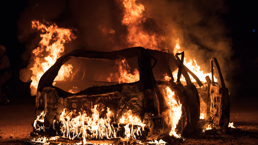 Suasana dramatik sebuah kenderaan elektrik yang diliputi api, menunjukkan api yang marak dan asap yang menjulang dari kereta yang terbakar. Gambar ini menekankan risiko yang berpotensi berkaitan dengan kebakaran kenderaan elektrik, menarik perhatian kepada isu keselamatan.